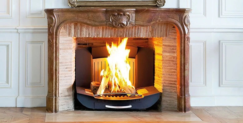 Insert moderne noir dans une vieille cheminée en petite briques rouges blanchies, couronnée d'un ornement de cheminée ancienne.